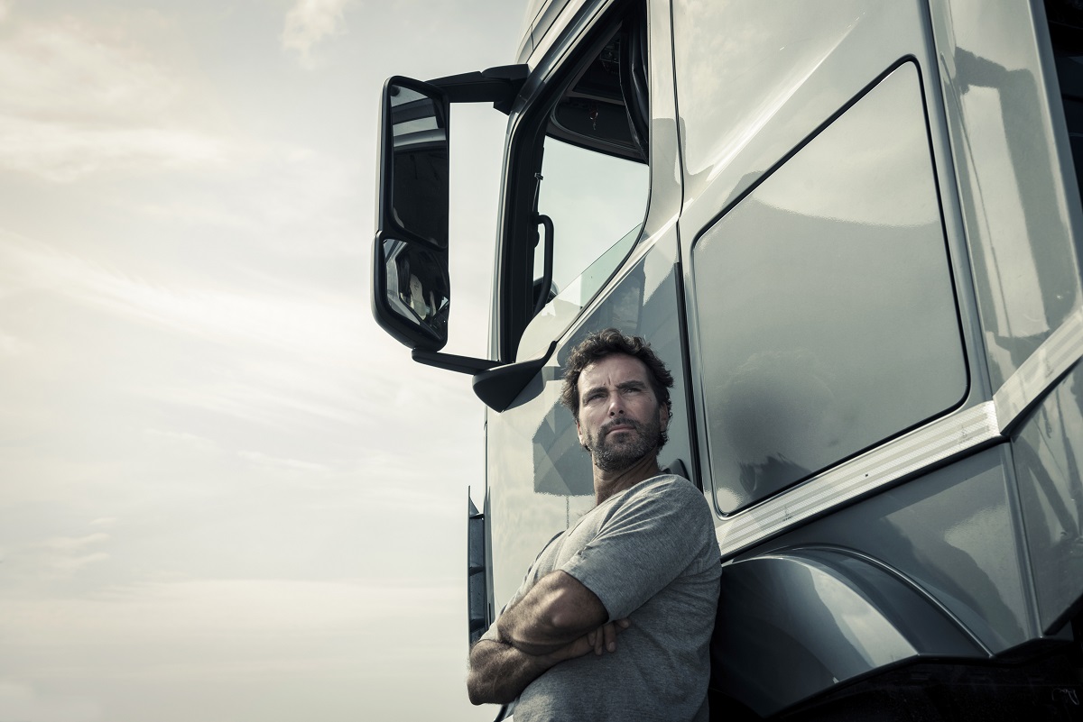 Truck driver posing beside a silver truck