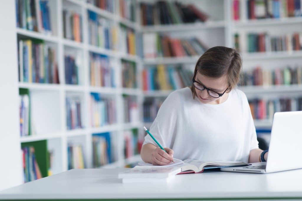 white bookshelves background with woman studying with laptop