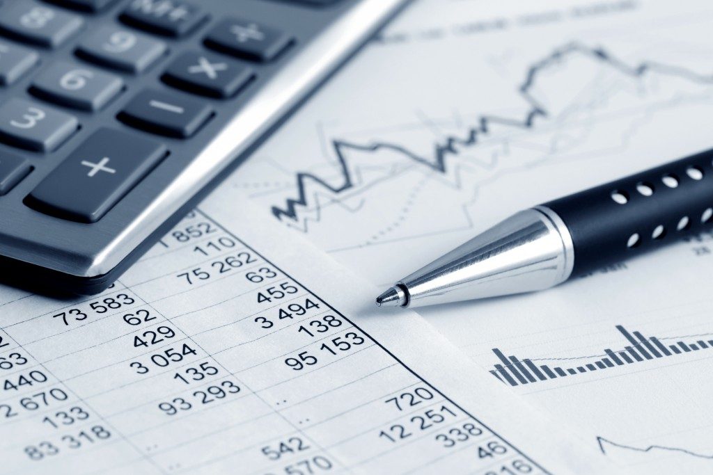 finance document showing numbers and charts with a pen and calculatoron top