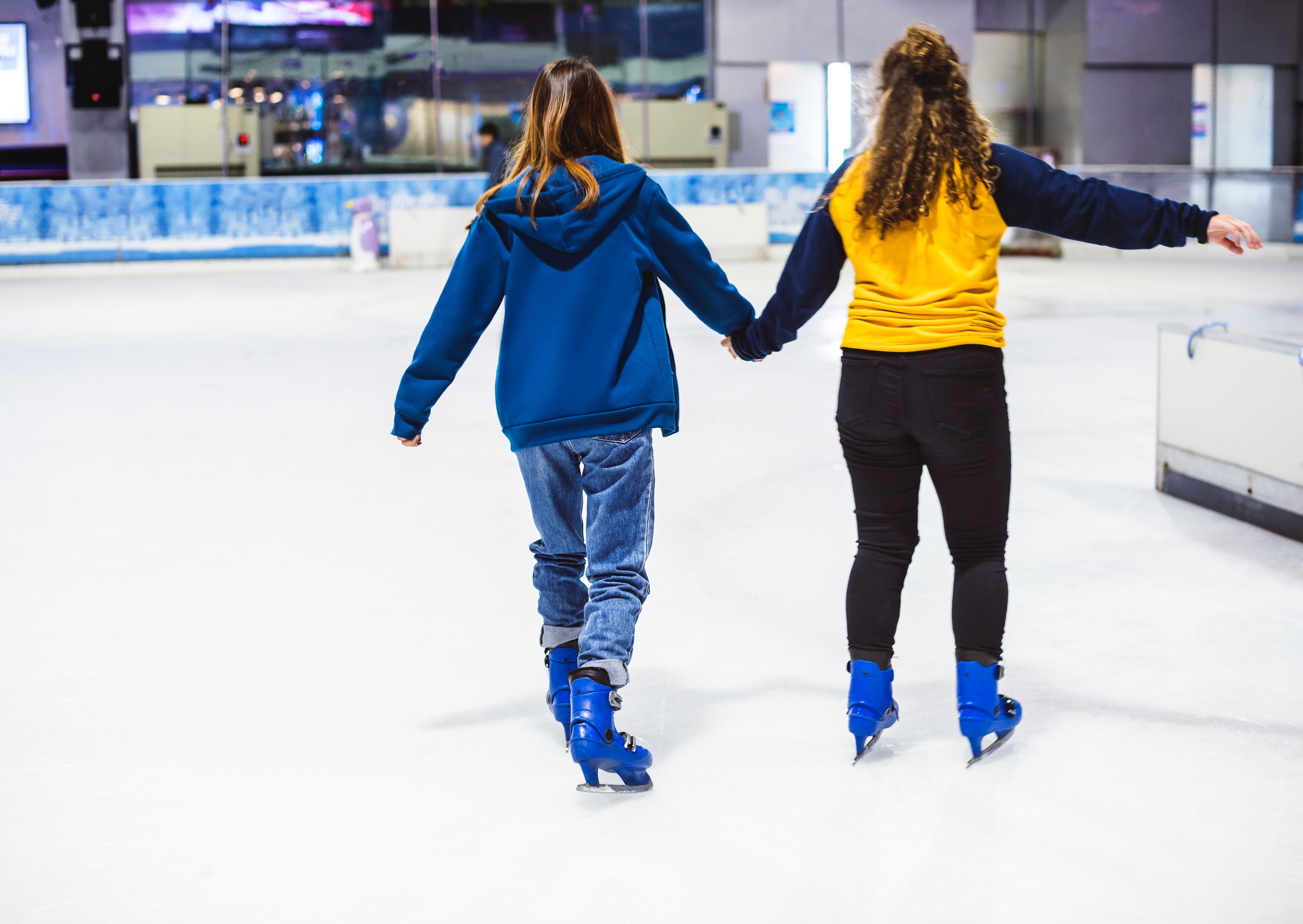 Two girls holding hands trying not ot fall on the ice