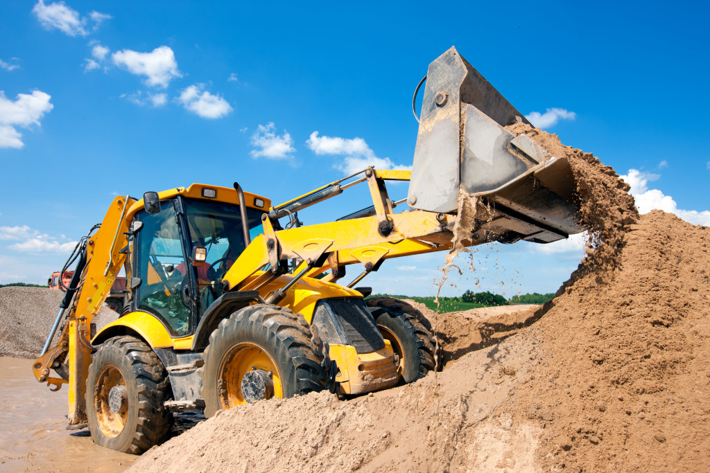 A yellow wheel loader excavator excavating soil on a construction site